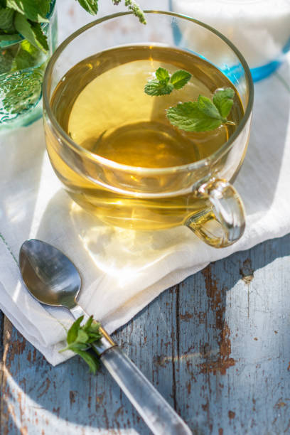Fresh mint leaf tea in a glass cup on a wooden table, healthcare and healthy eating concept